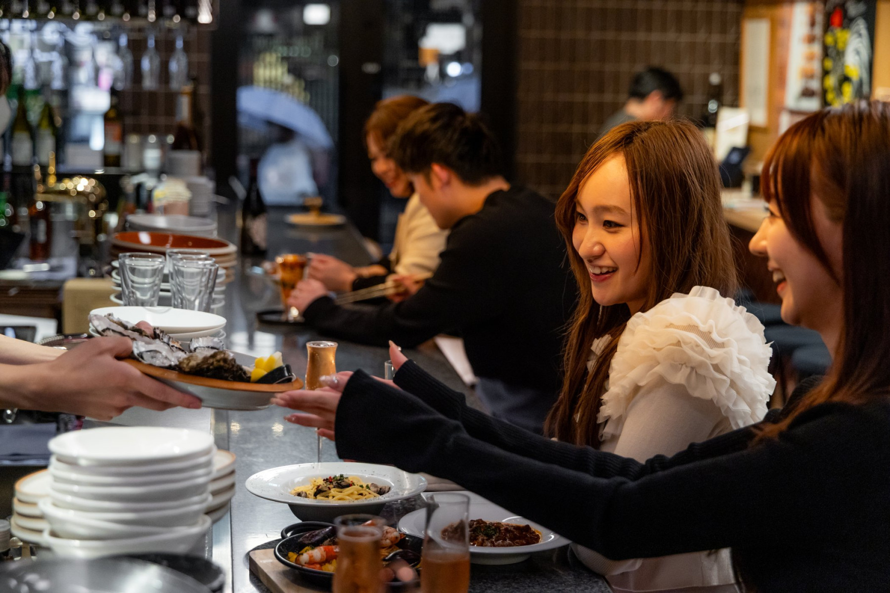 TOKYO Oyster PUB akasakaのカウンターで料理を受け取る様子